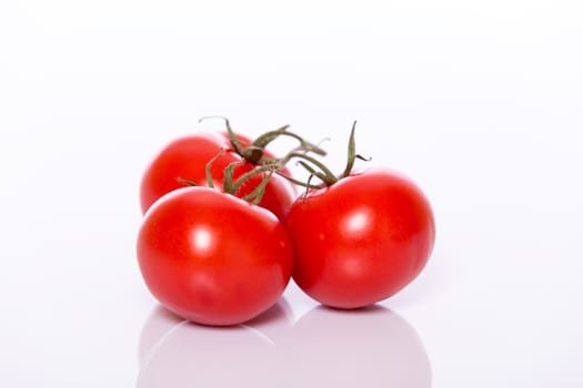 Three shiny round red tomatoes in grape