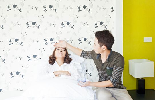 Young adult husband takecare his sick wife in bedroom (selective focus at woman)
