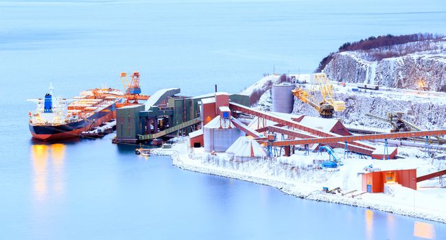 Panorama Industrial Container Cargo freight ship with working crane in shipyard at Iron Ore Mine Factory Plant in Narvik Norway