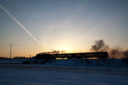 Vintage steam train puffing through countryside during wintertime
