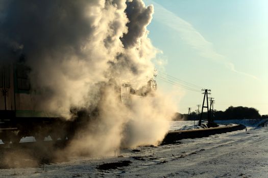 Vintage steam train puffing through countryside during wintertime
