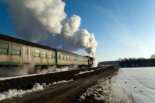 Vintage steam train puffing through countryside during wintertime
