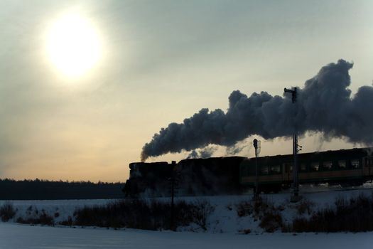 Vintage steam train puffing through countryside during wintertime
