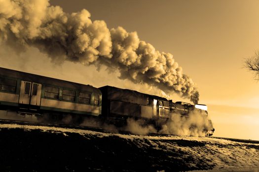 Vintage steam train puffing through countryside during wintertime
