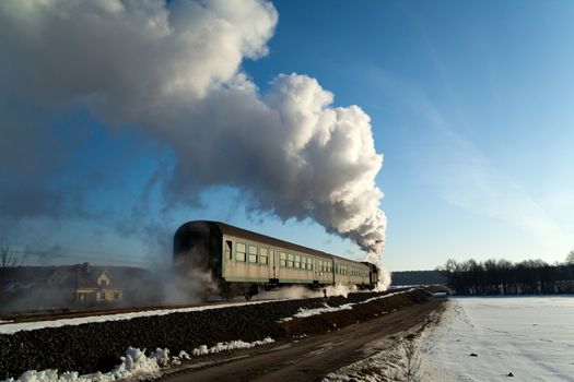 Vintage steam train puffing through countryside during wintertime
