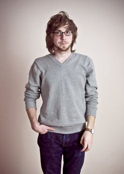 portrait young handsome man in glasses standing near the wall