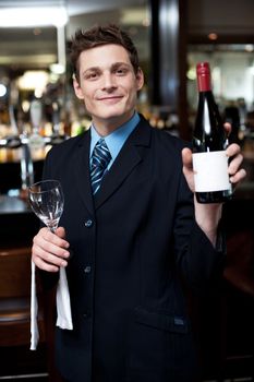 Smartly dressed young man showing you the alcohol bottle. Time to relax and enjoy...cheers