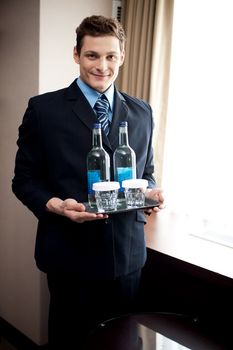 Male butler holding fresh beverages for customers. Posing in front of camera