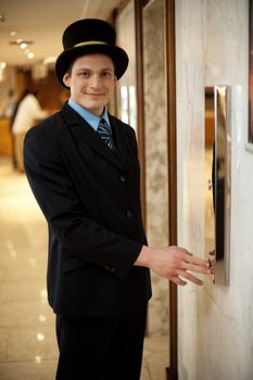 Profile shot of a doorman in a bowler hat waiting near the elevators