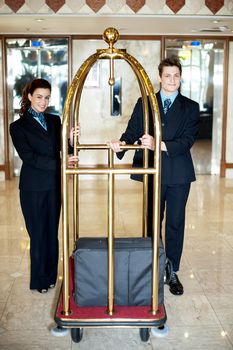 Concierge colleagues holding baggage cart with luggage on it