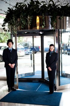 Door man with receptionist at the entrance. Parking area in background