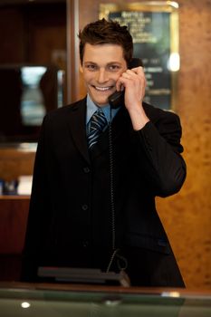 Calm and relaxed executive interacting over the phone and smiling at camera