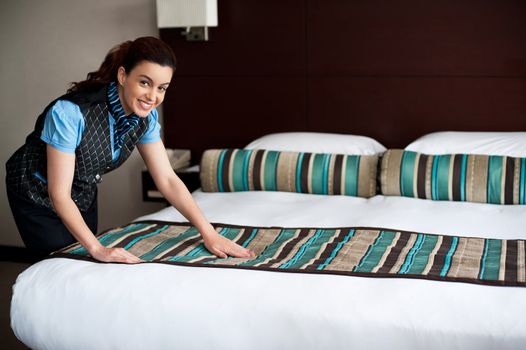 Elegant housekeeping lady adding final touches to bedroom before customer arrival
