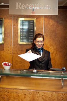 Female receptionist handing over check-out papers along with bill to the customer