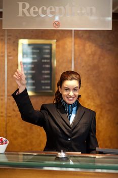 Beautiful female receptionist indicating upwards to show the direction instructions board