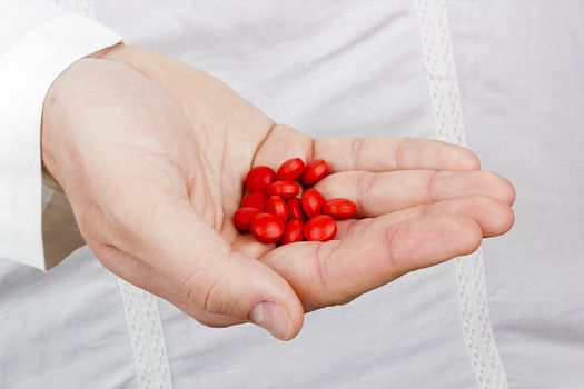 Close-up photograph of a hand holding red tablets.