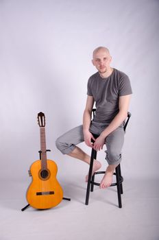 Nice bald guy with a guitar in the studio