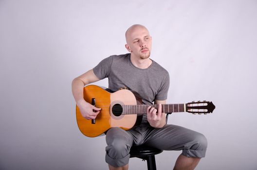 Nice bald guy with a guitar in the studio