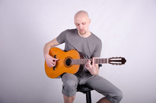 Nice bald guy with a guitar in the studio