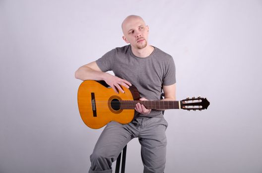 Nice bald guy with a guitar in the studio