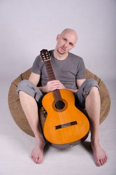 Nice bald guy with a guitar in the studio