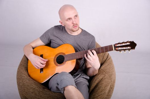 Nice bald guy with a guitar in the studio