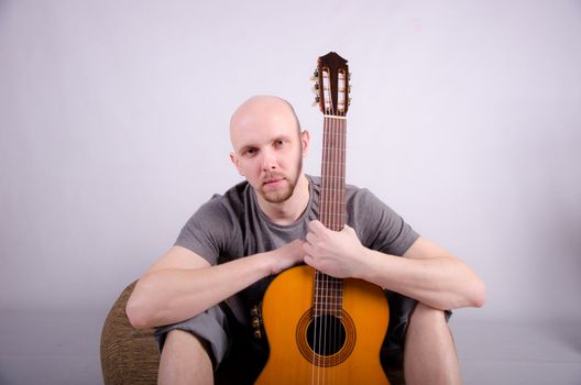 Nice bald guy with a guitar in the studio