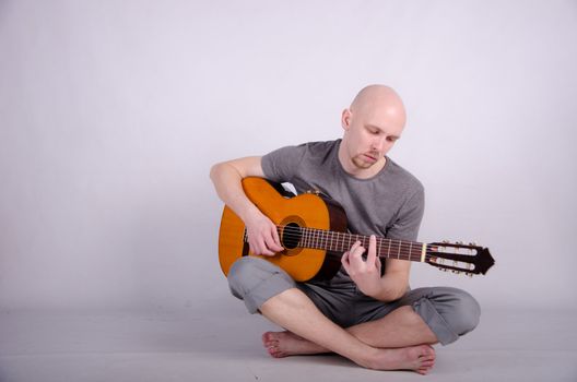 Nice bald guy with a guitar in the studio