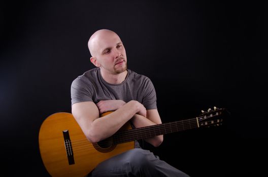 Nice bald guy with a guitar in the studio