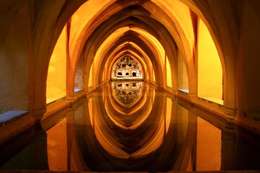 Image perspective of the underground pond, beneath the Royal Alcazar in Seville. The light and reflections in the water create an image of great beauty.