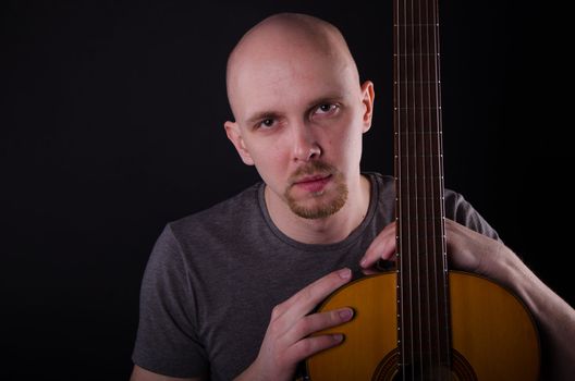 Nice bald guy with a guitar in the studio