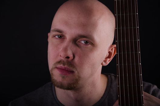 Nice bald guy with a guitar in the studio