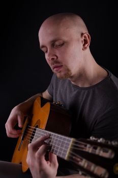 Nice bald guy with a guitar in the studio