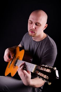 Nice bald guy with a guitar in the studio