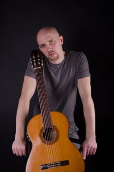 Nice bald guy with a guitar in the studio