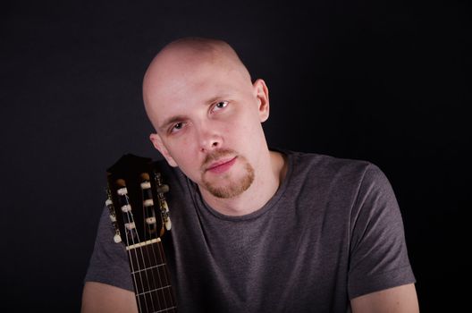 Nice bald guy with a guitar in the studio