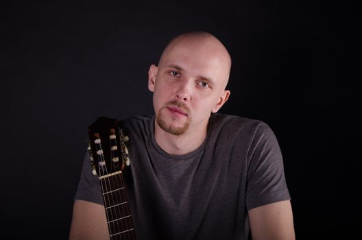 Nice bald guy with a guitar in the studio