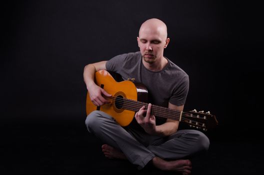 Nice bald guy with a guitar in the studio