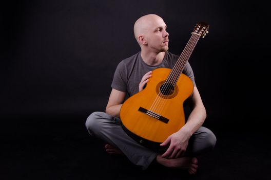 Nice bald guy with a guitar in the studio