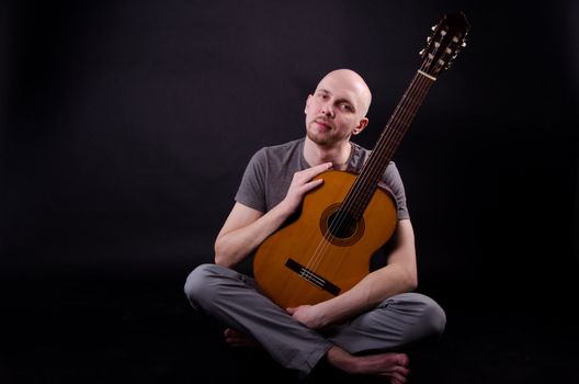 Nice bald guy with a guitar in the studio