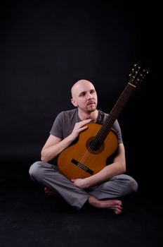 Nice bald guy with a guitar in the studio