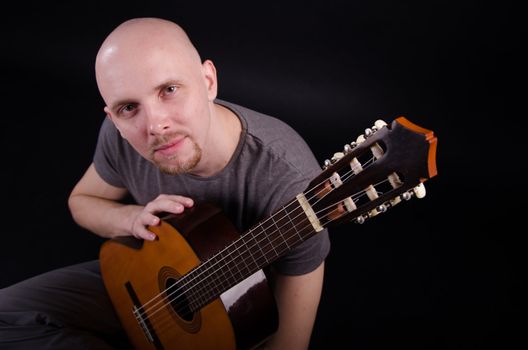 Nice bald guy with a guitar in the studio