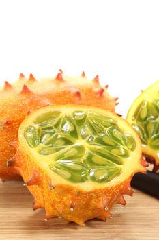 horned melon on a wooden board in front of light background