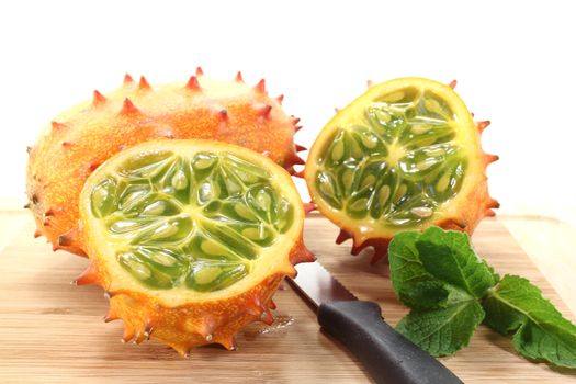 sliced horned melon on a wooden board in front of light background