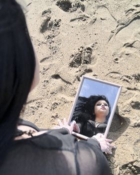 Woman reflected on a mirror on the sand