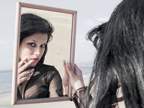 Young pretty woman at beach, viewed through a mirror