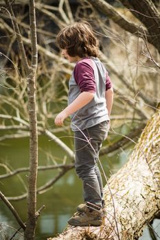 Boy standing on a tree over a river