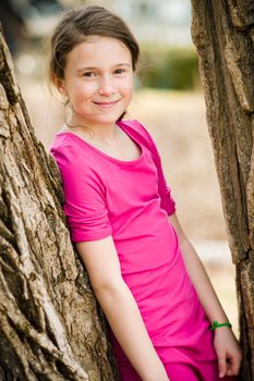 Young girl standing between two trees