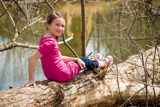 Girl sitting on a tree over a river