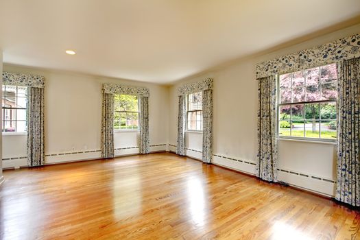 Large empty room with hardwood floor and curtains. Old luxury American house.